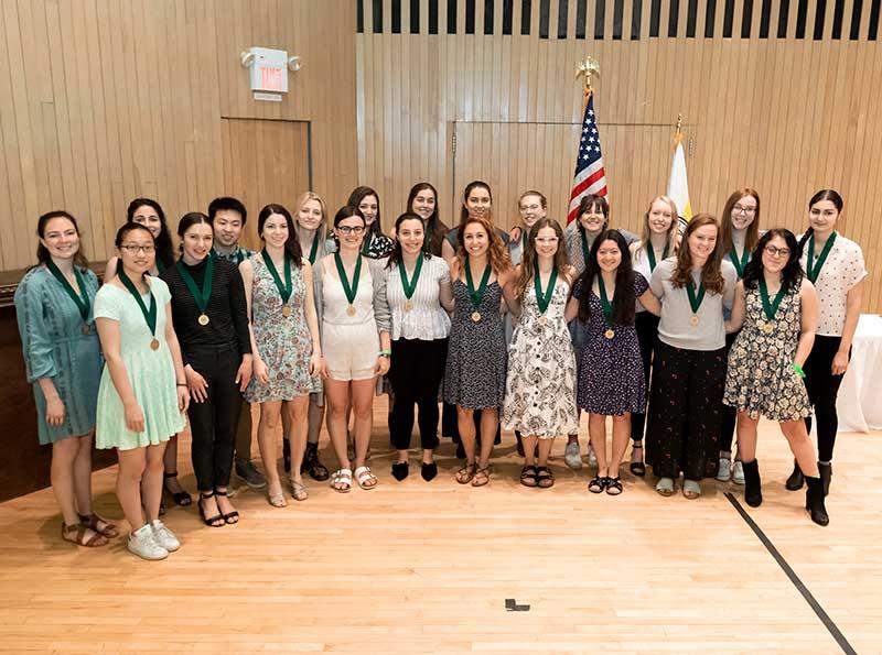 22 students pose for a group photo all wearing medals