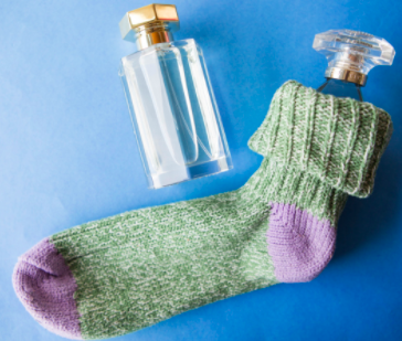 one glass perfume bottle is tucked inside a cotton sock. A second perfume bottle sits next to the pair.